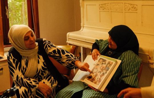 foto van 2 vrouwen aan de piano met een boek 